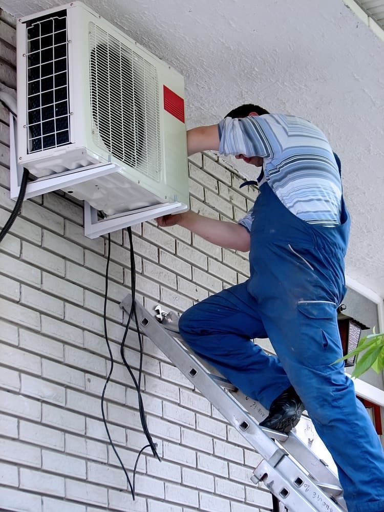 A Man Is Working on A Residential Air Conditioner — Gordon's Air Conditioning & Refrigeration Services in Caloundra, QLD