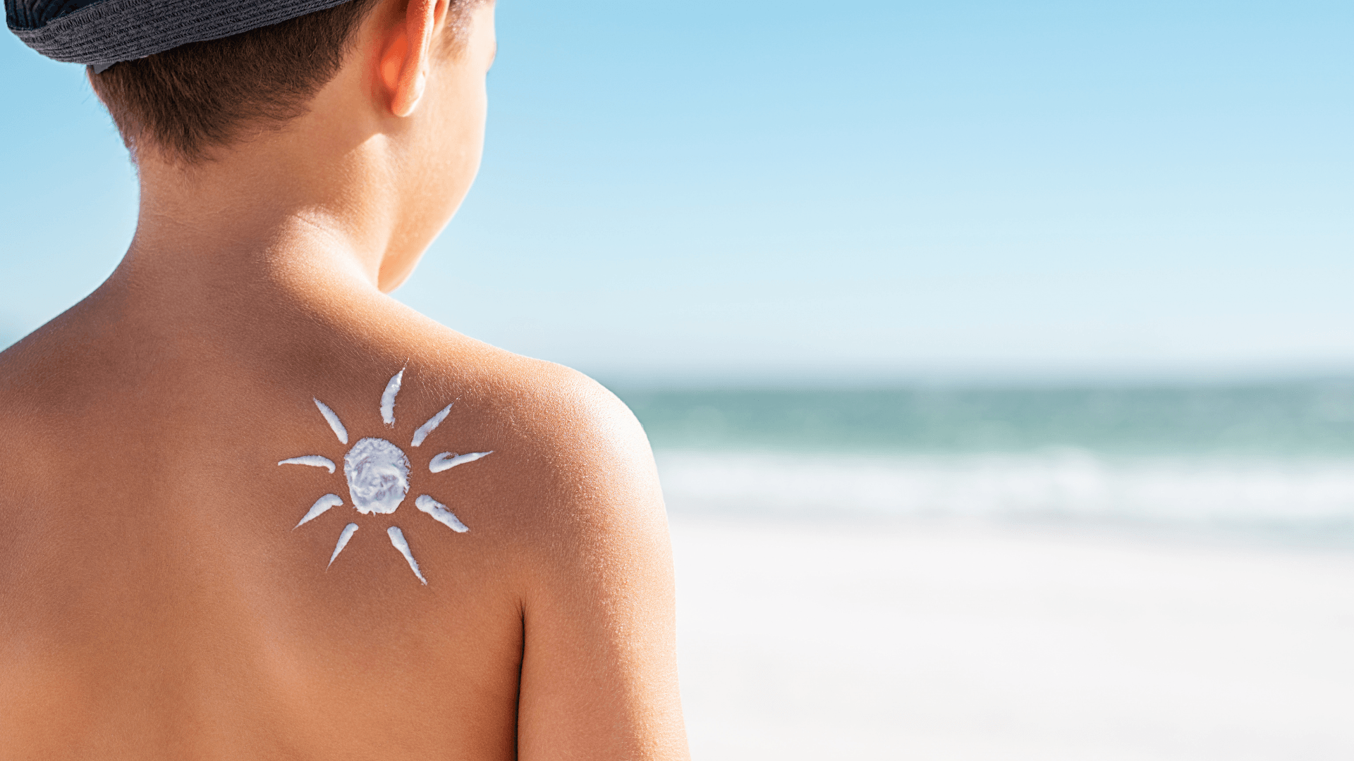 a young boy has a sun drawn on his back with sunscreen .