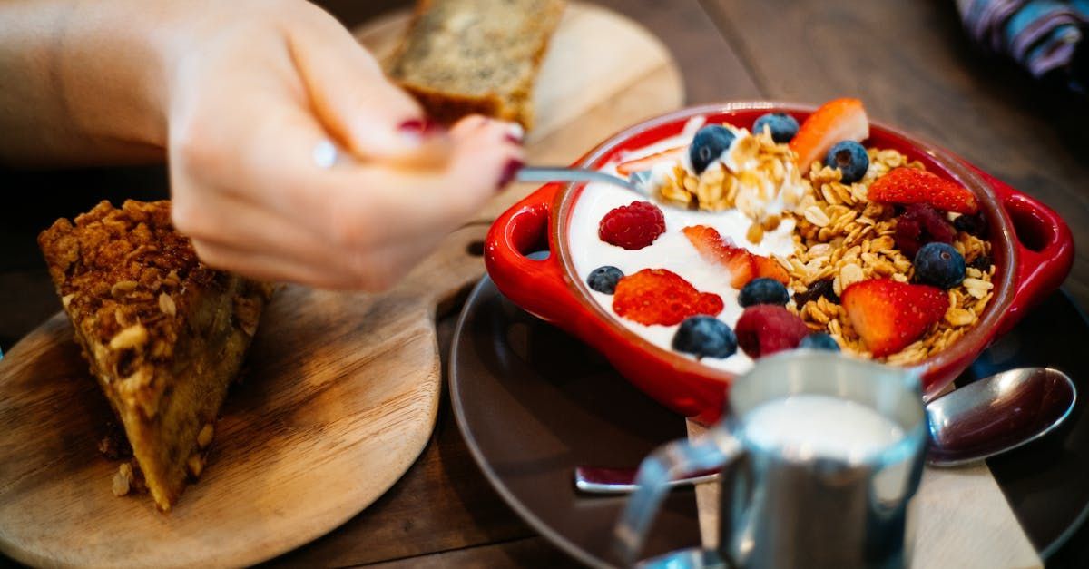 A person is eating a bowl of granola with yogurt and berries.