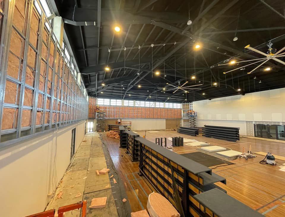 Gym under construction, with exposed insulation, metal framing, and a partially finished floor.