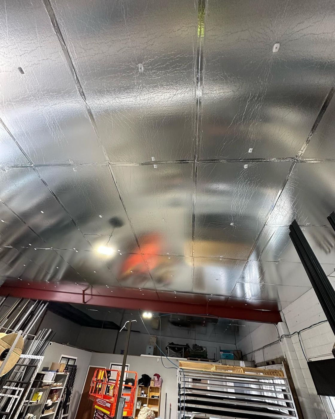 Galvanized metal ceiling in a workshop with a red beam and tools on shelves below.
