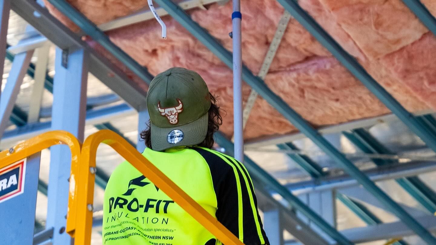 Person in neon safety vest, wearing a Chicago Bulls cap, working on a construction project with insulation.