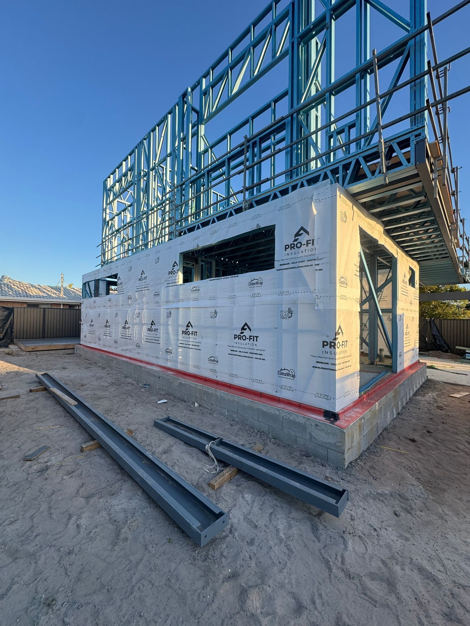 Steel frame construction of a building on a concrete foundation; daytime.