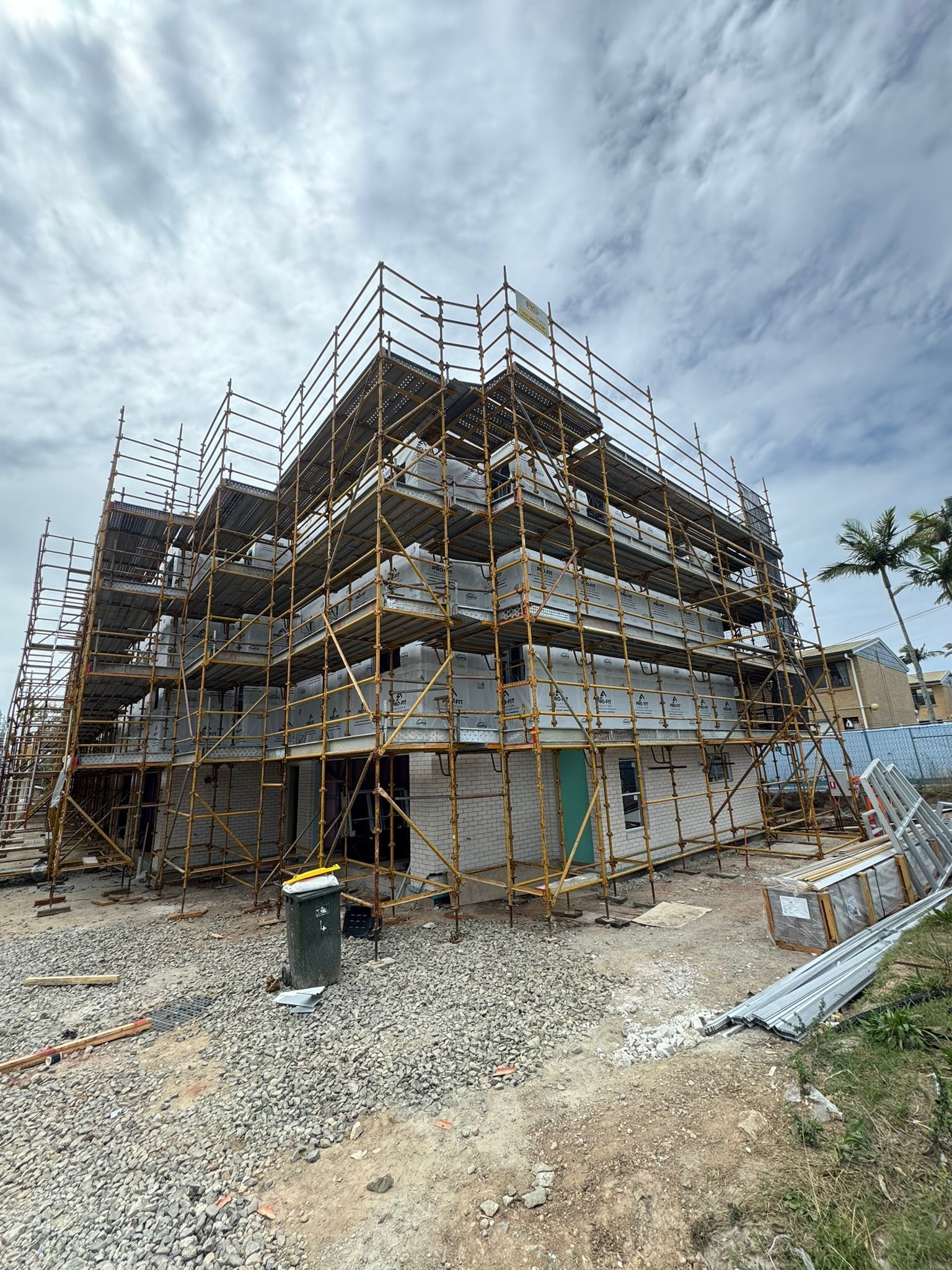 Building under construction with scaffolding against a cloudy sky.