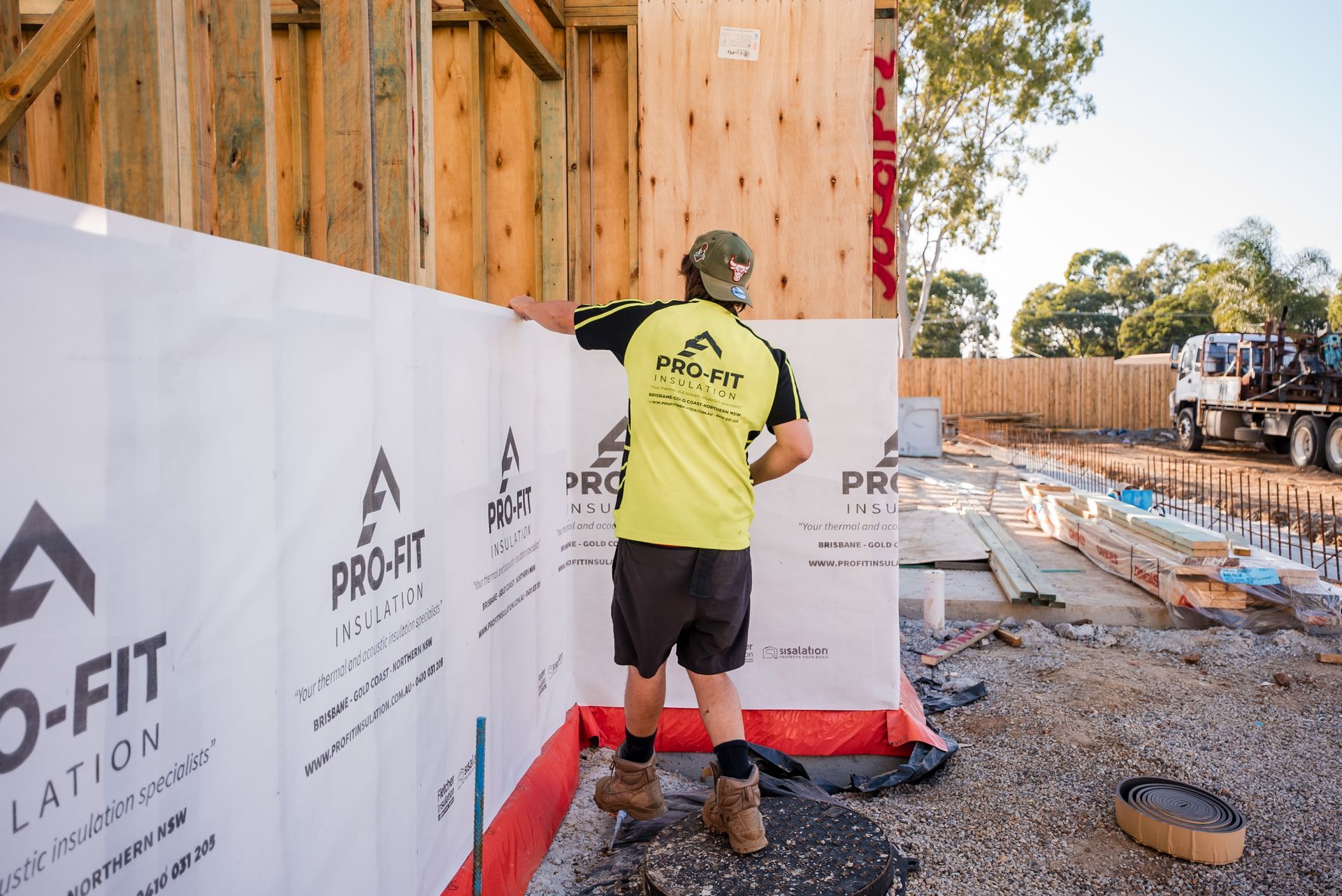 Construction site with teal sheathing, scaffolding, and concrete foundation.