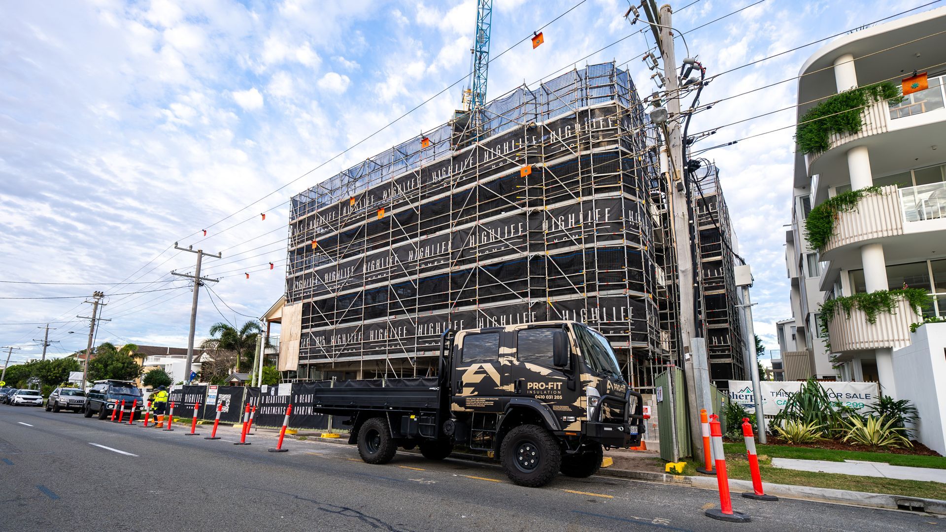 Construction site with a camouflage truck parked on the street. Building surrounded by scaffolding.