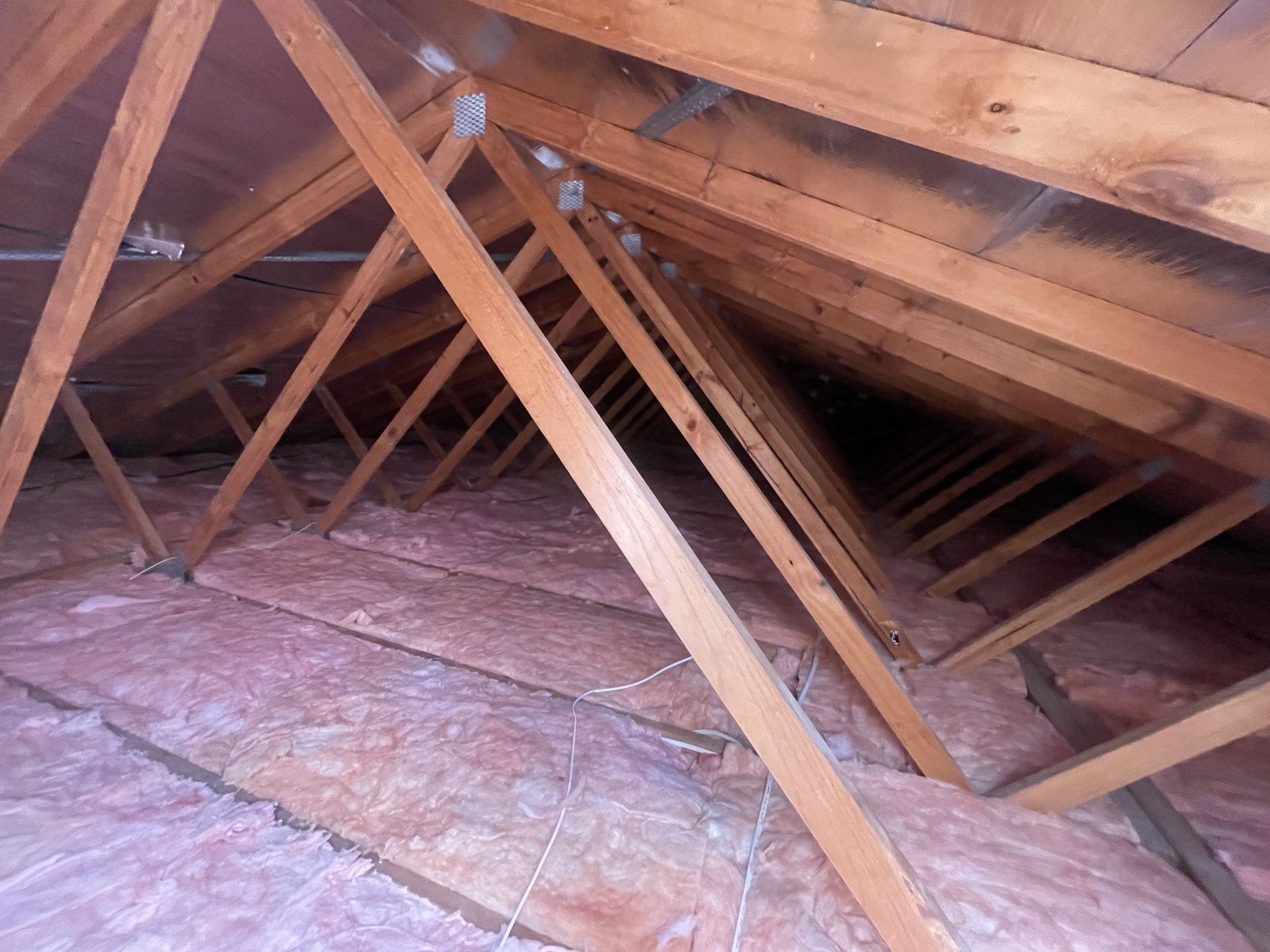 Wooden attic rafters with pink insulation visible.