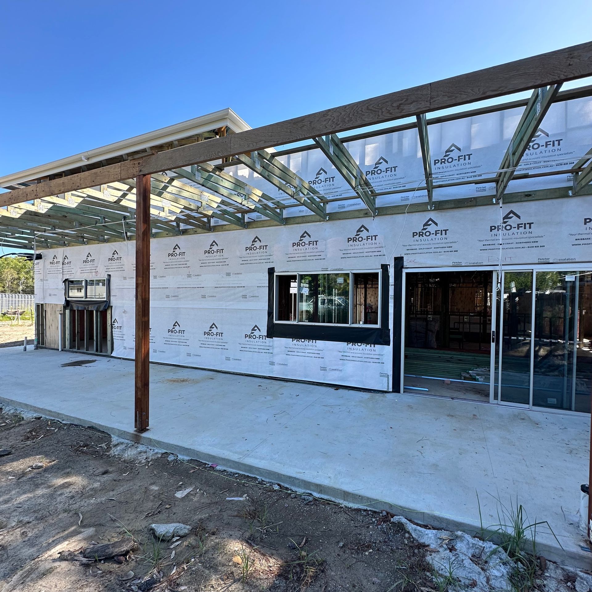 Building under construction, exterior view. Concrete base, walls with white insulation.