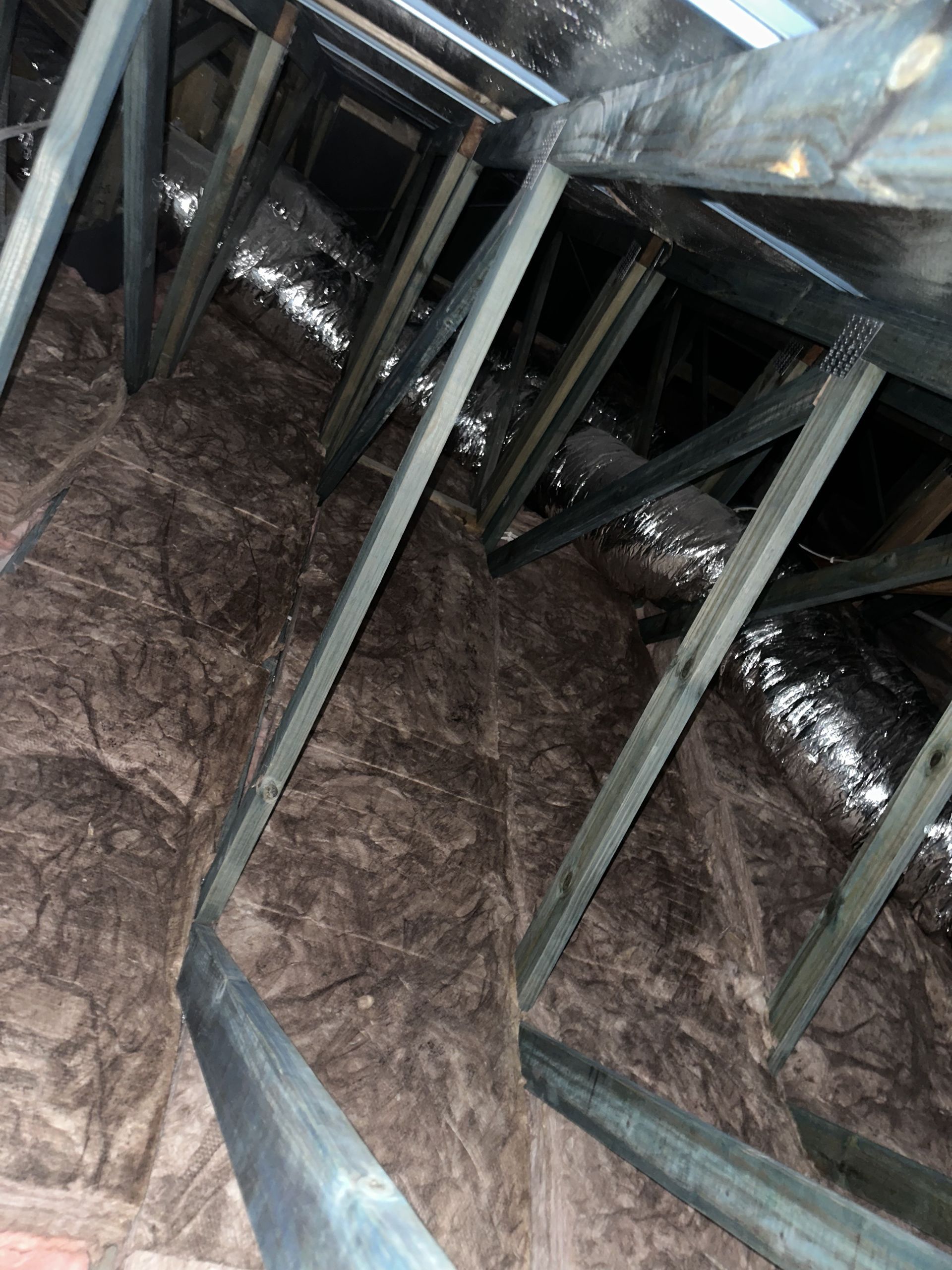 Interior view of an attic space. Wooden rafters and insulation cover walls.