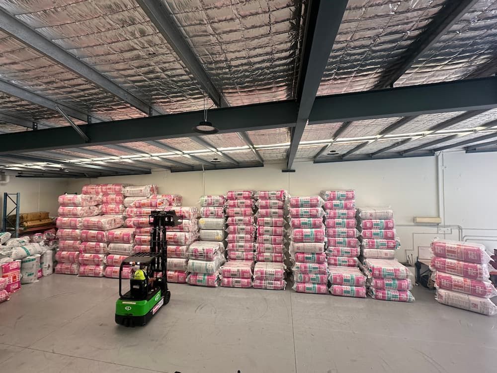 Forklift in a warehouse with stacked pink insulation.