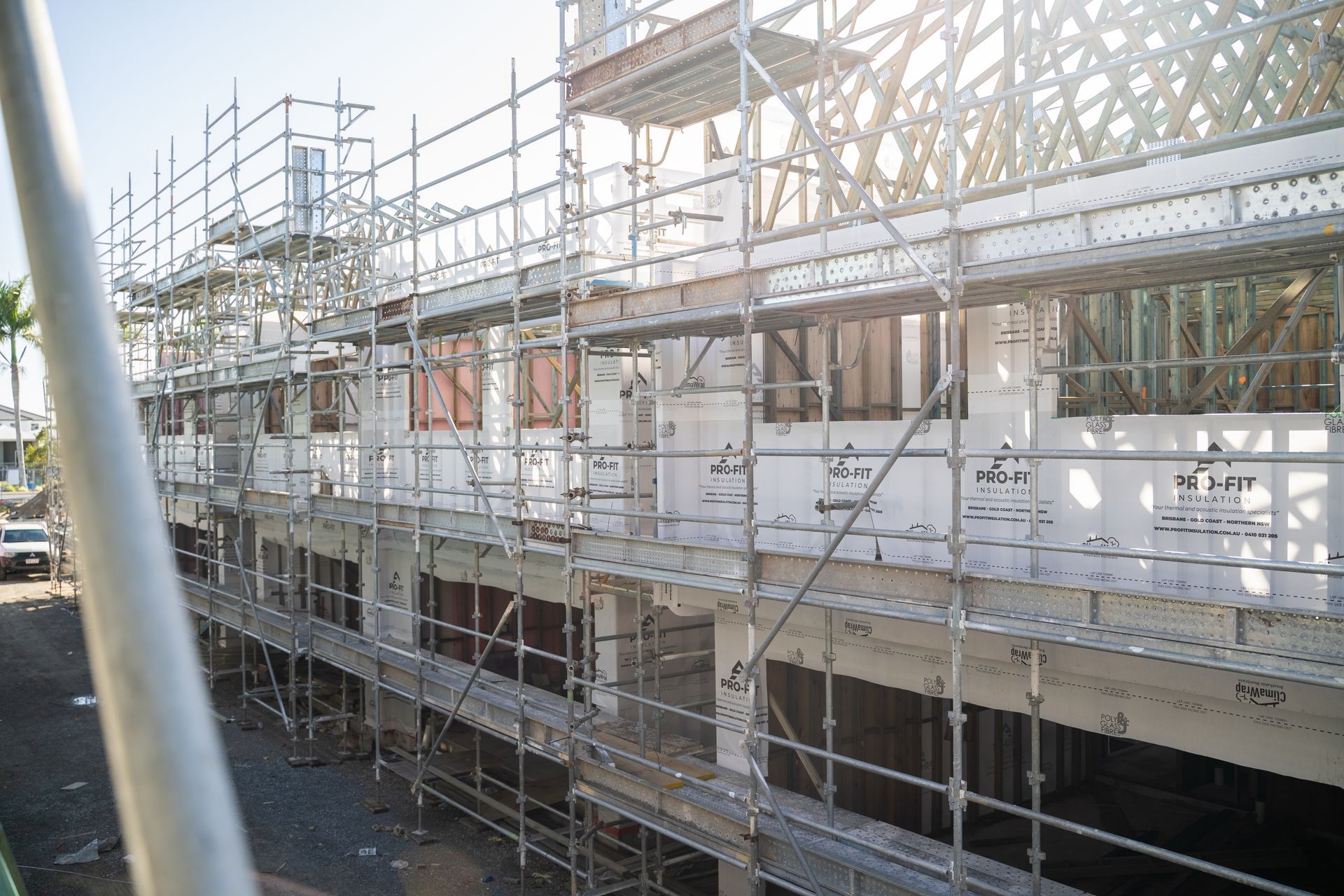 Building under construction, scaffolding, unfinished walls, bright sunlight.