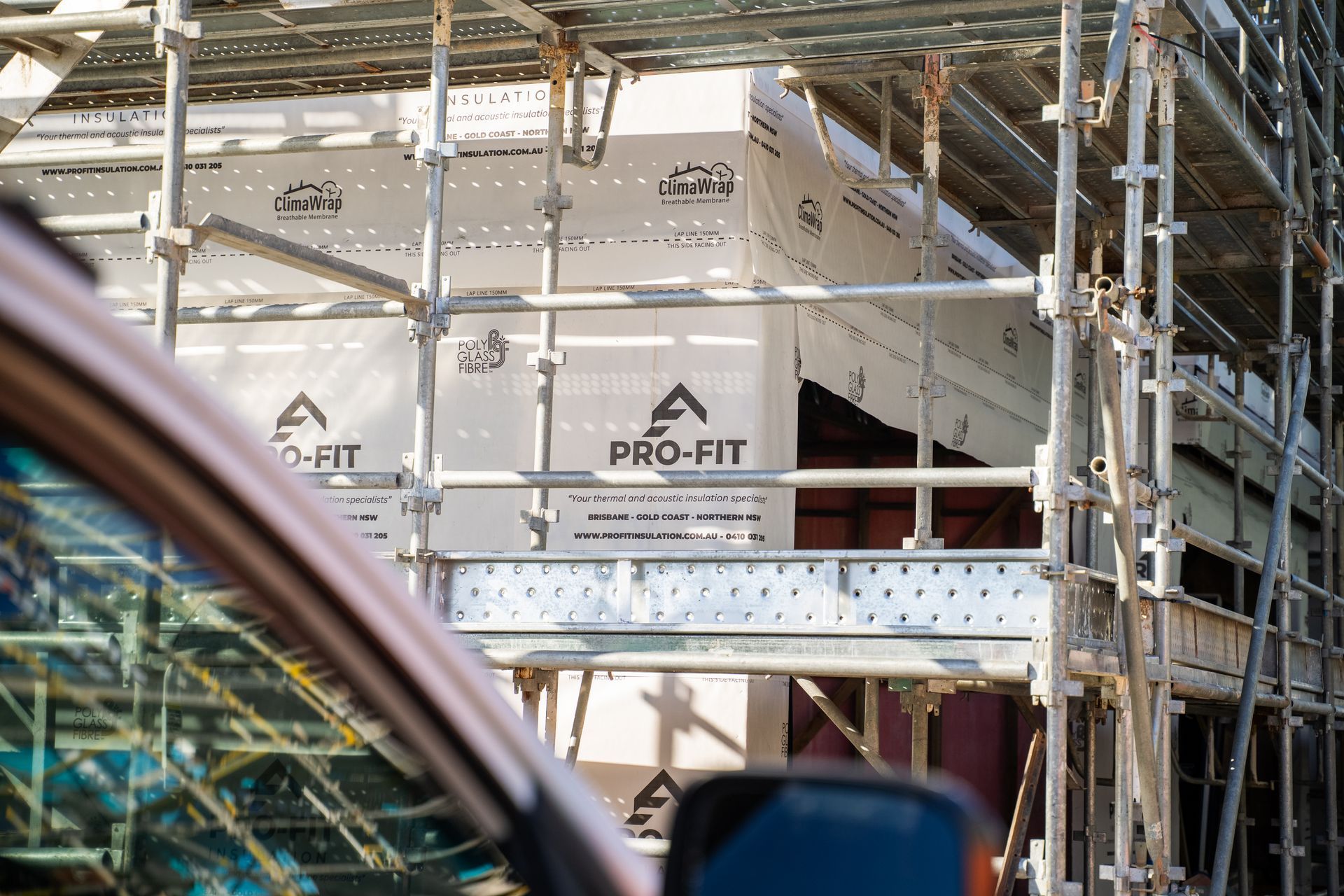 Scaffolding surrounds a building under construction, with visible PRO-FIT signage.