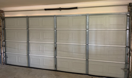 Closed white garage door with metal frame, inside a garage.