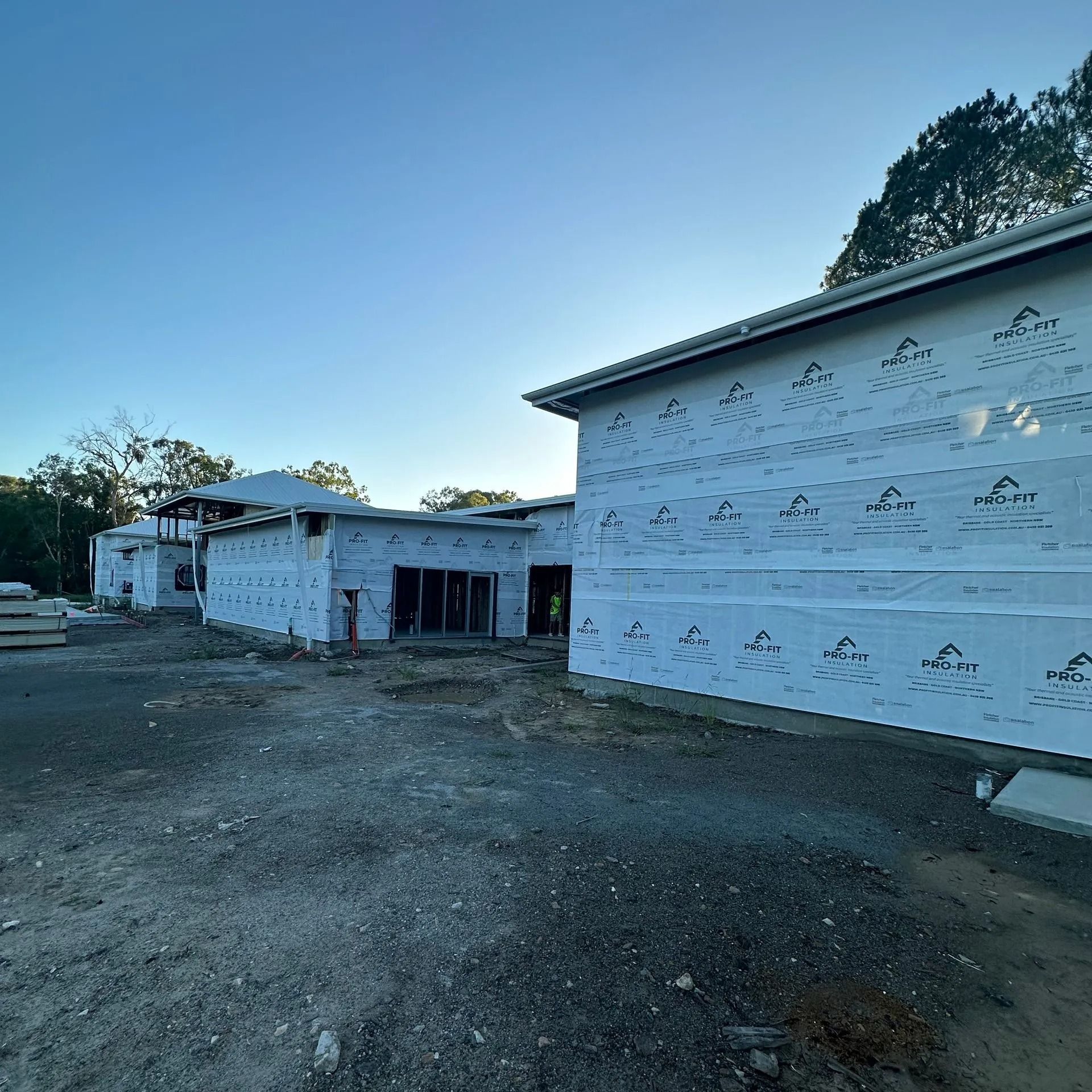 Construction site with buildings in progress, covered in white sheathing. Sunny day.