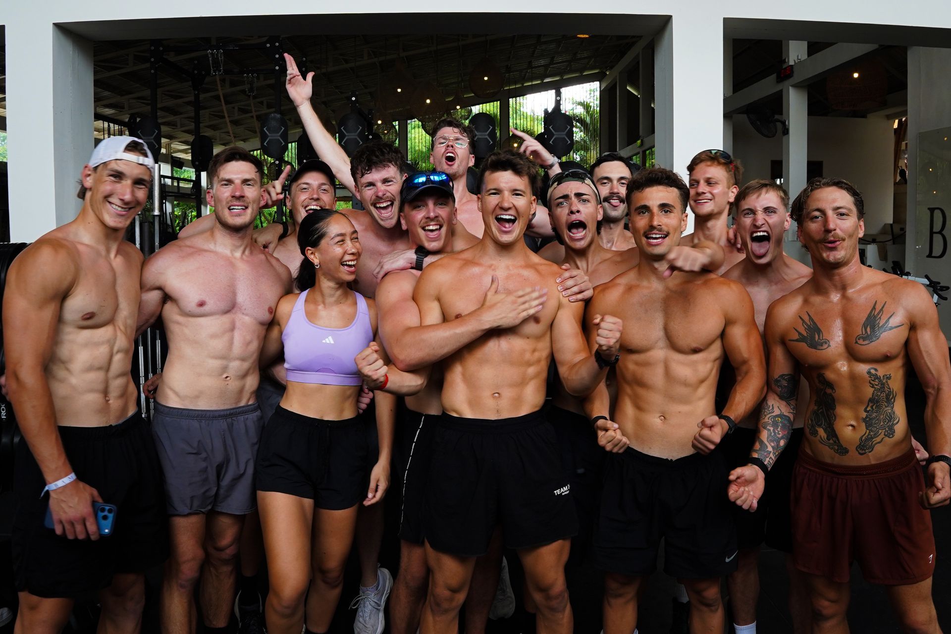 A group of shirtless men are posing for a picture in a gym.