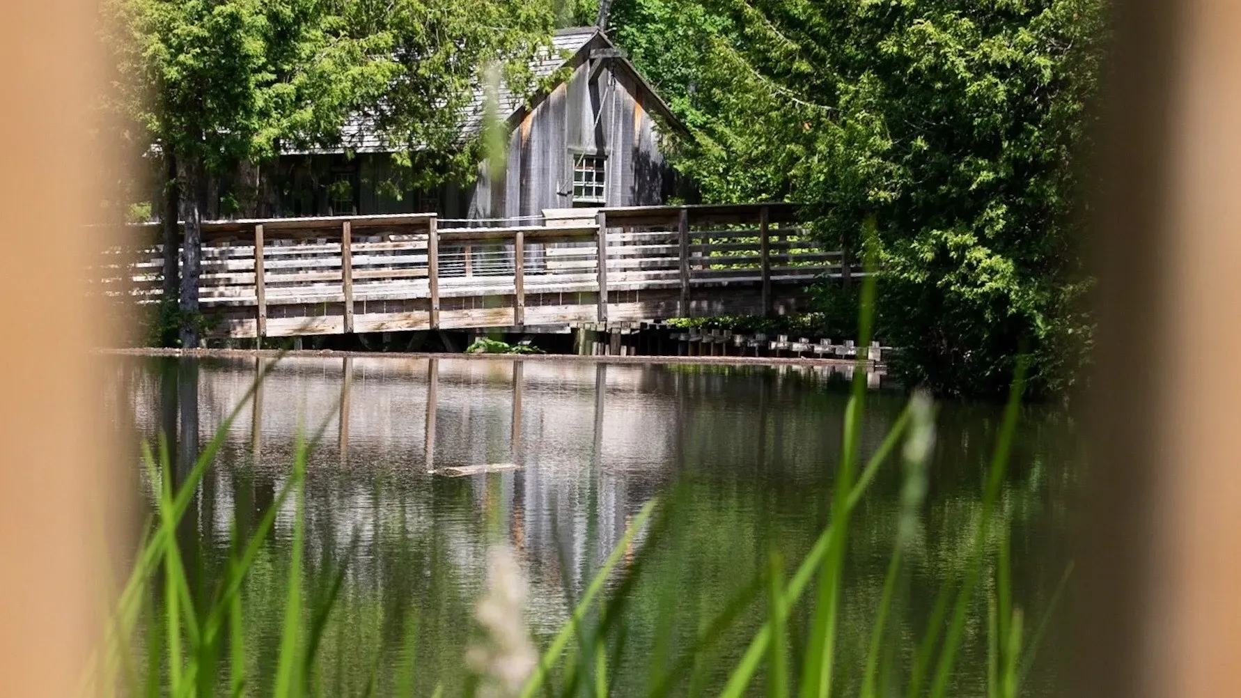 A bridge over a lake with a house in the background