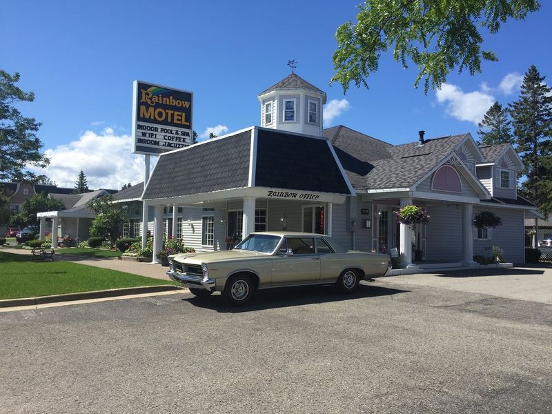 A white car is parked in front of a motel.