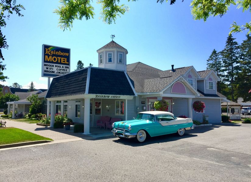 A blue car is parked in front of a motel