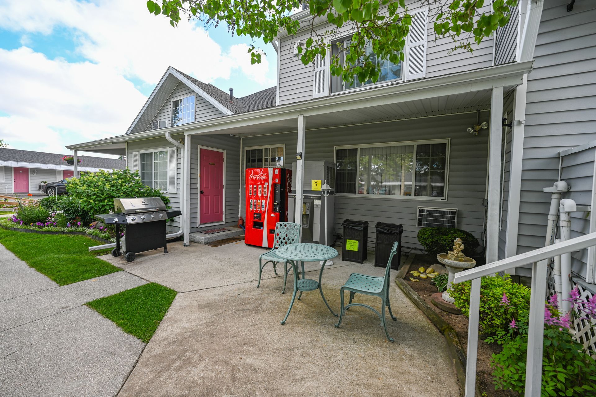 There is a coca cola machine on the porch of a house.