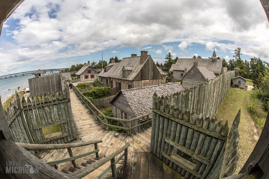 A fisheye lens shows a village with a wooden fence and houses.