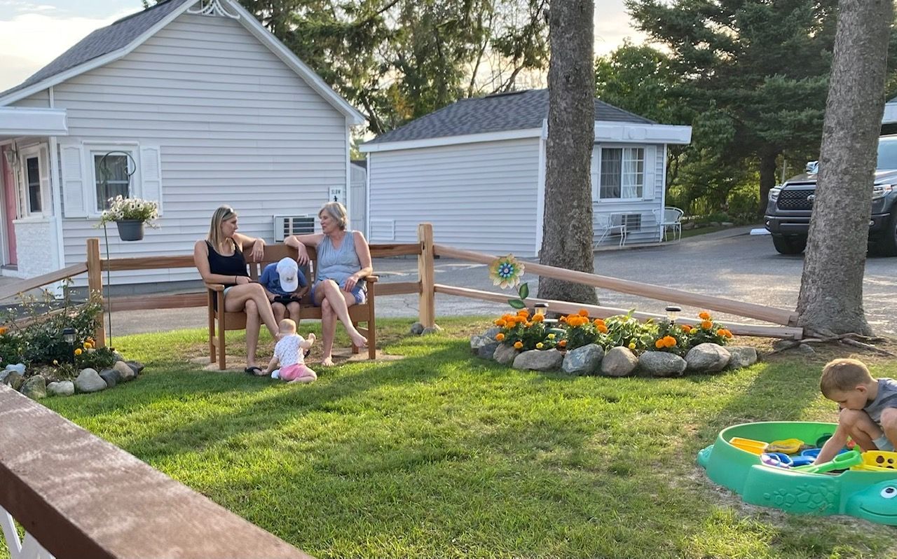 A group of people are sitting on a bench in front of a house.