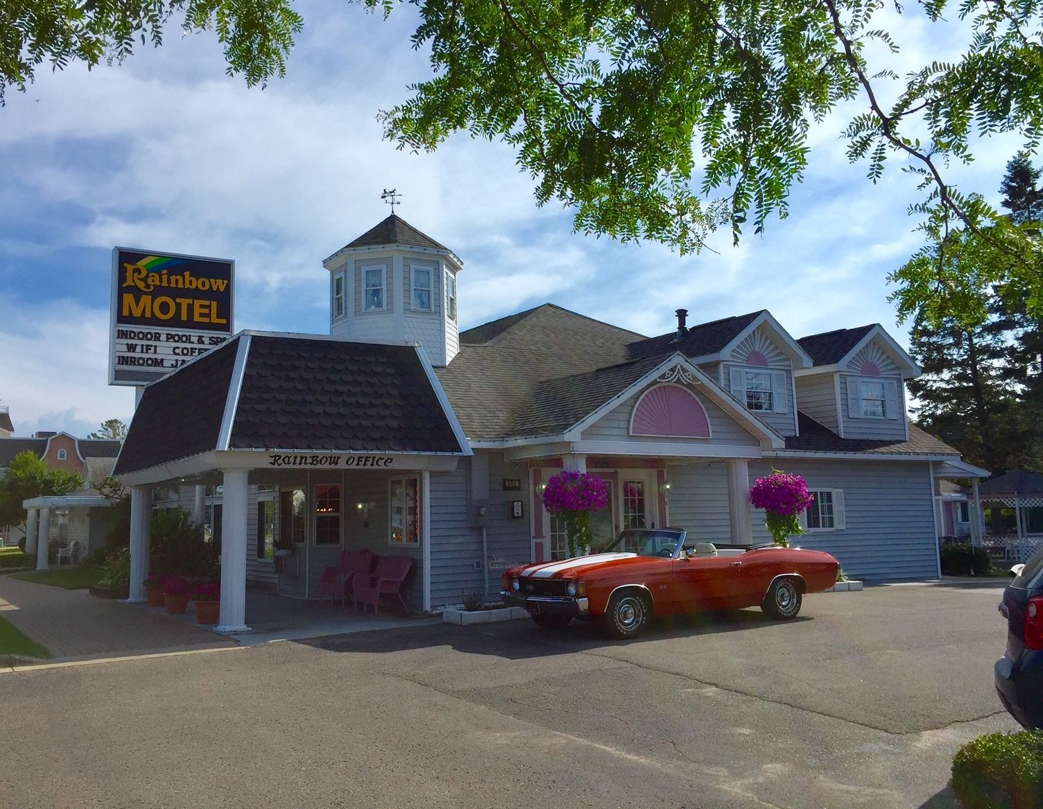 A red car is parked in front of a motel