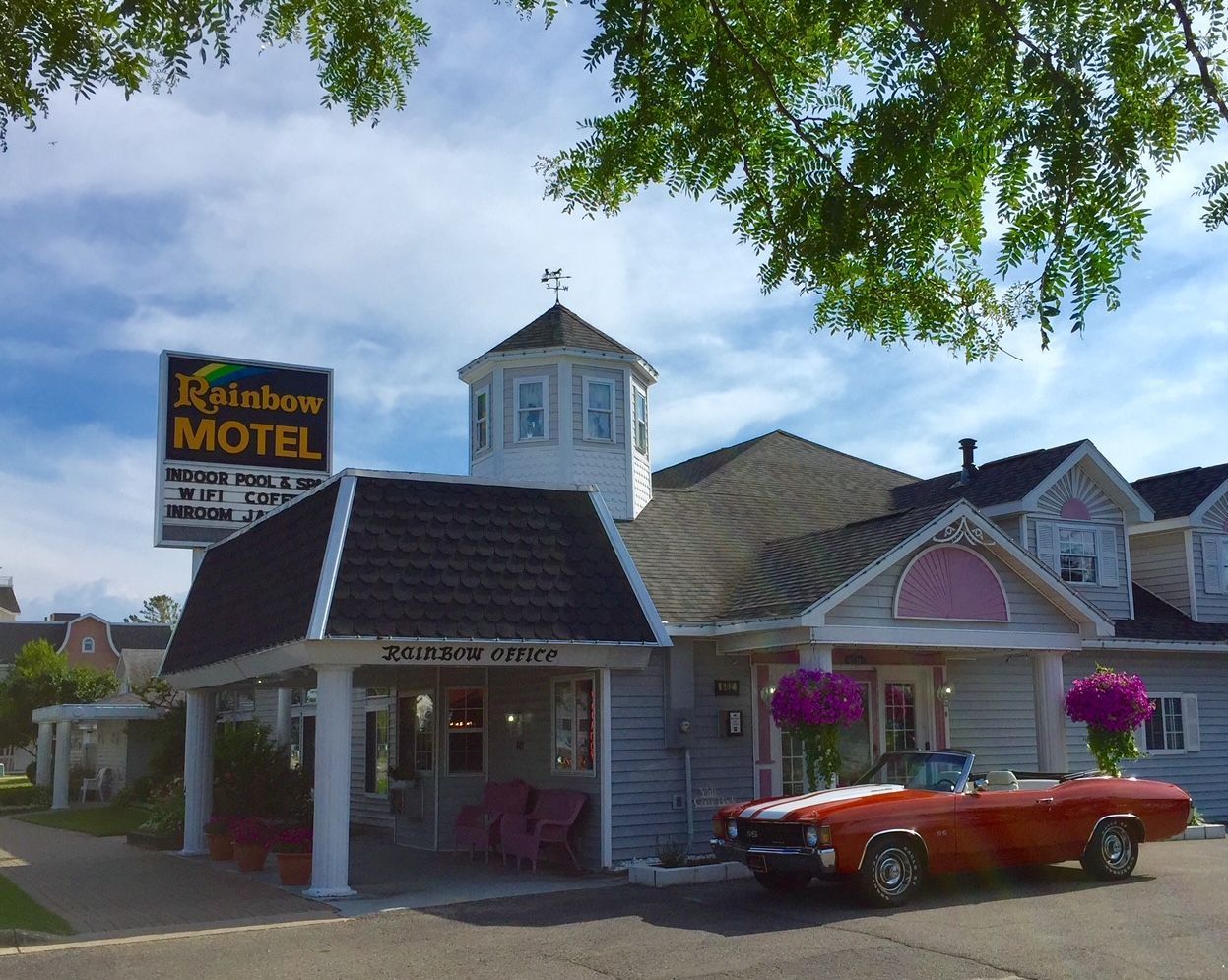 A red car is parked in front of a motel