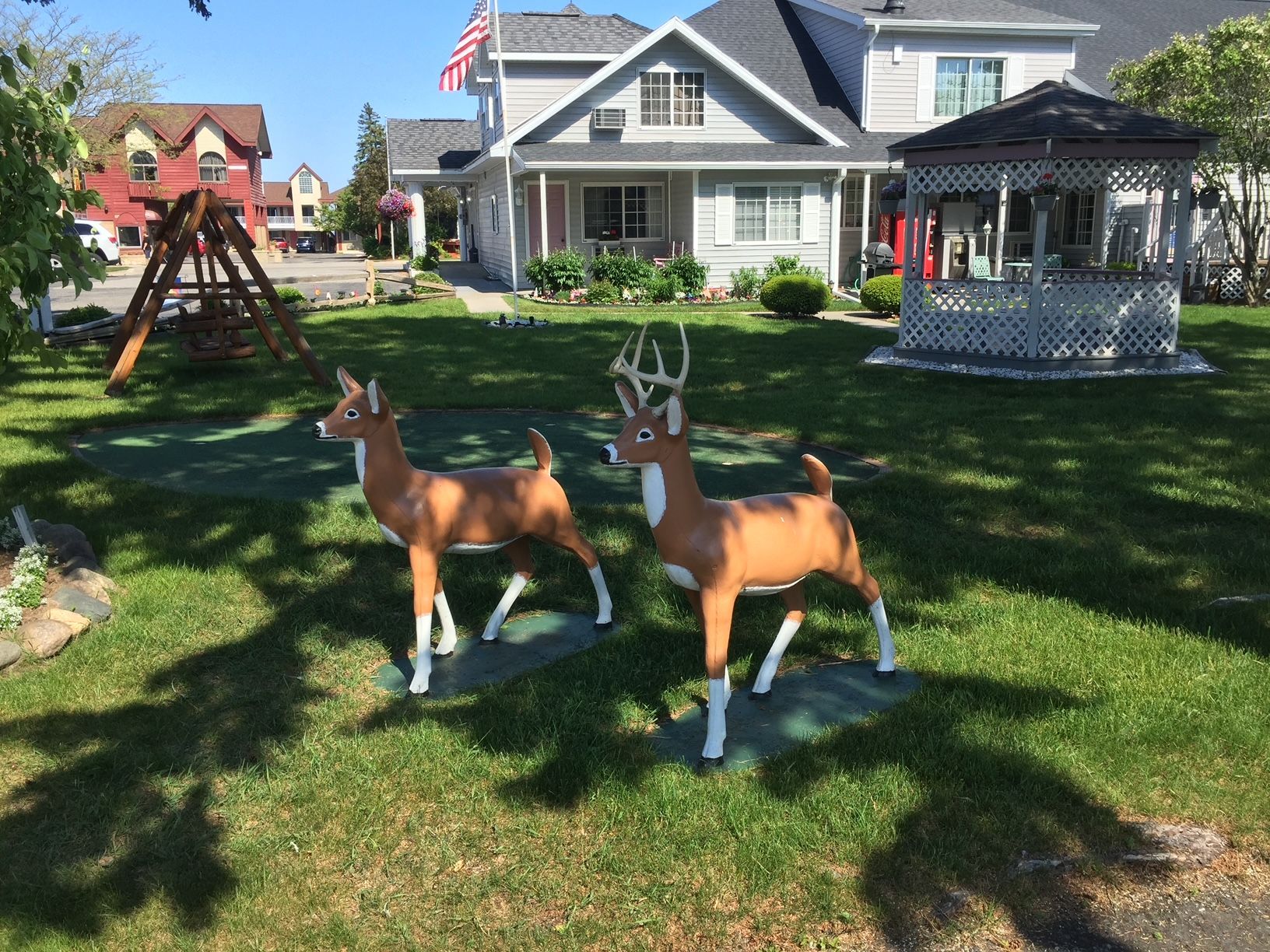 Two deer statues are in the grass in front of a house.