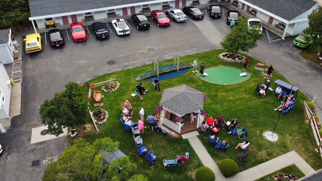 A group of people are sitting around a gazebo in a yard.