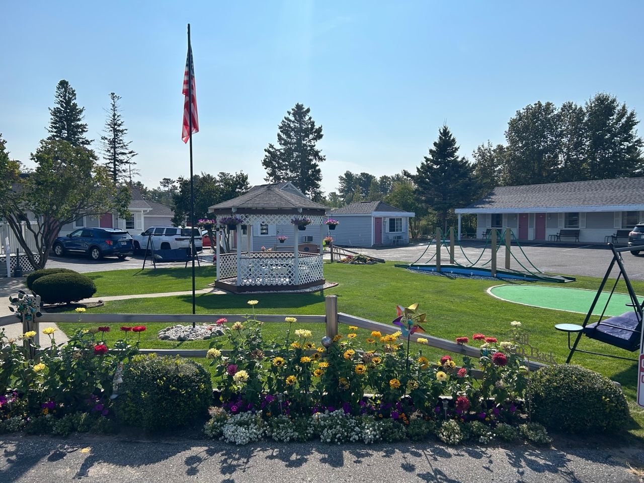A garden with flowers and a swing in front of a house
