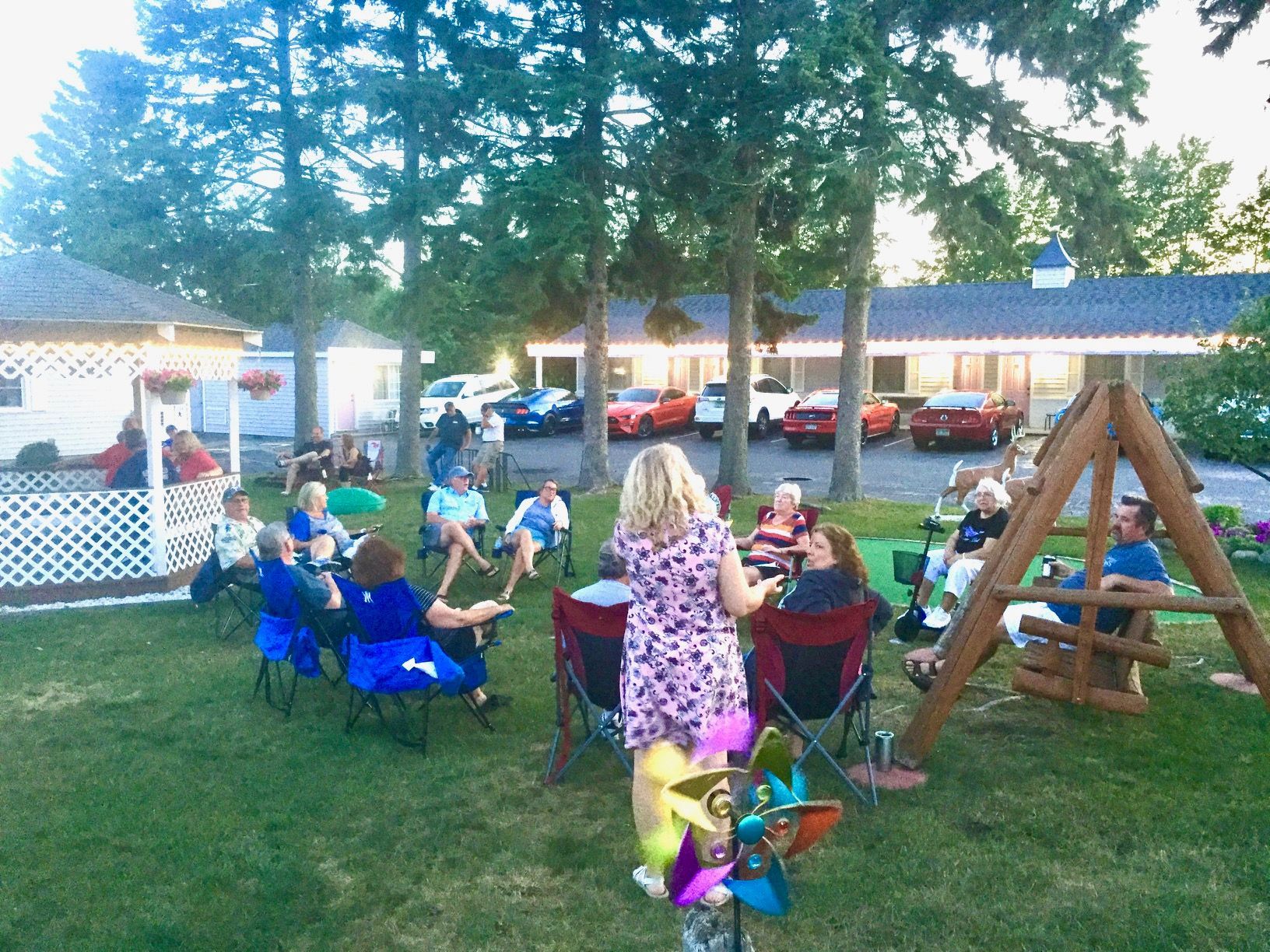 A group of people are sitting around a table in a yard.