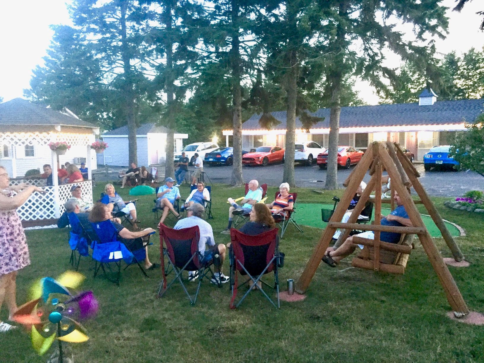 A group of people are sitting around a fire pit in a yard.