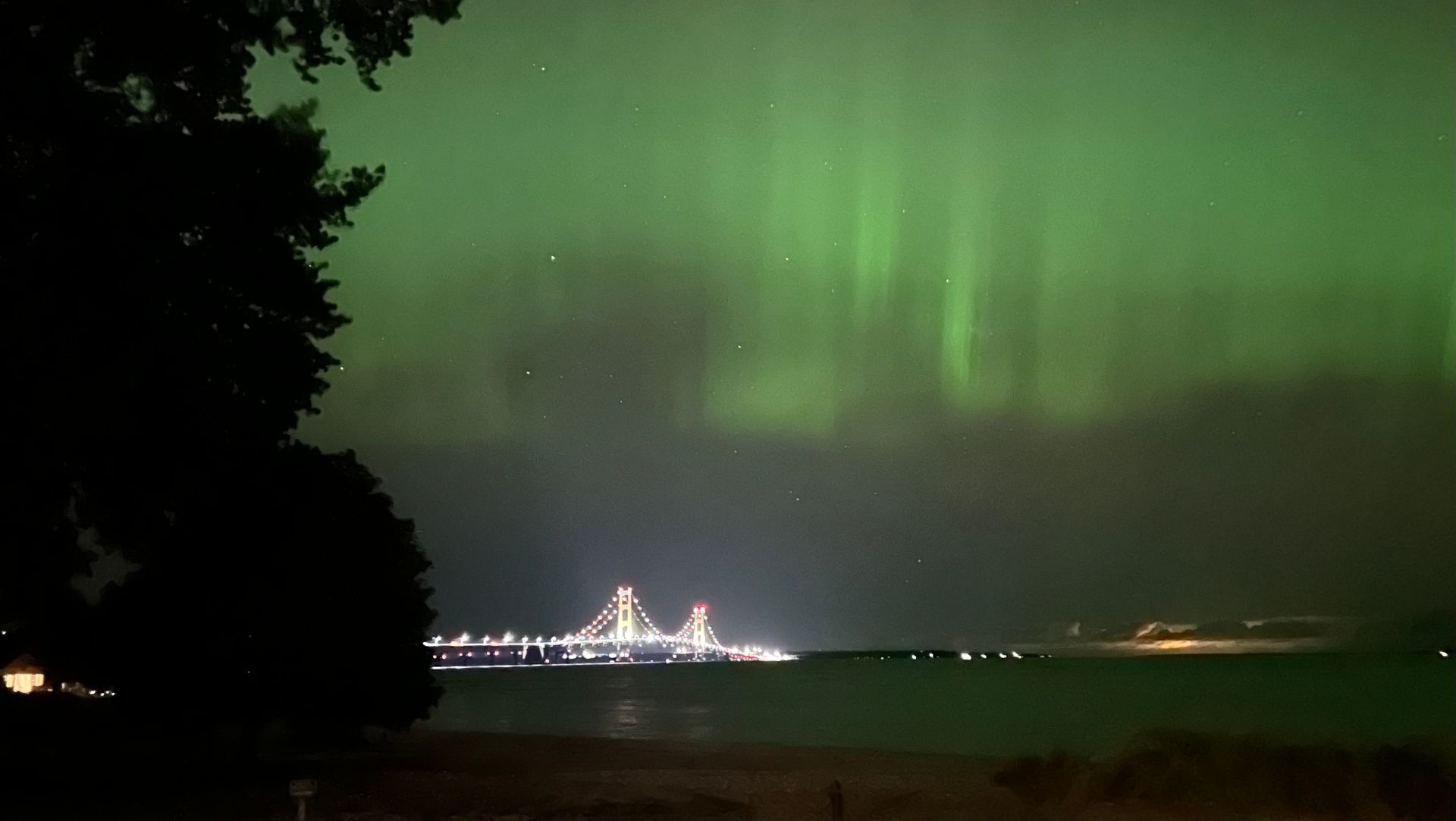 The aurora borealis is visible over a bridge in the distance.