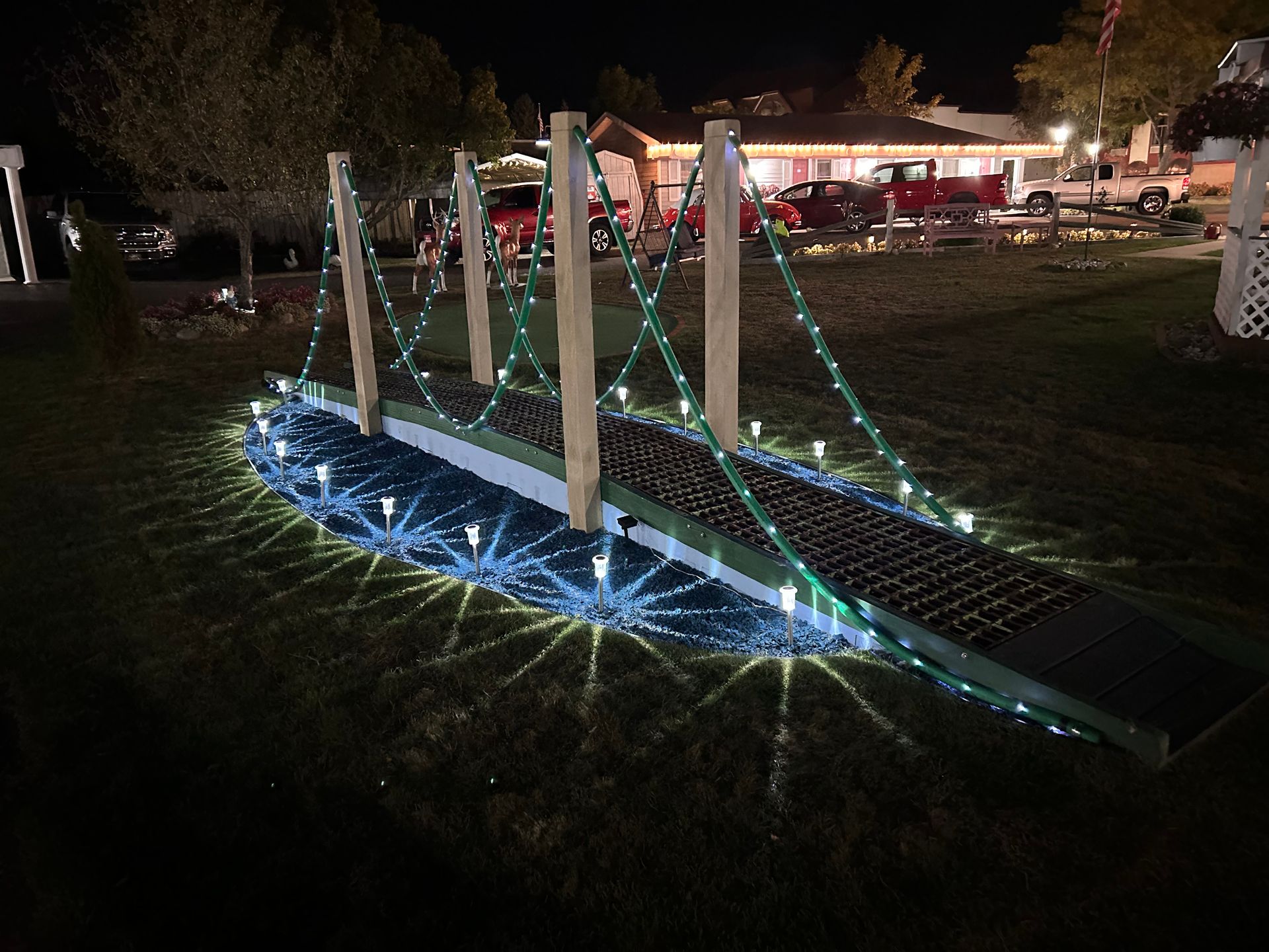 A small bridge decorated with christmas lights is lit up at night.