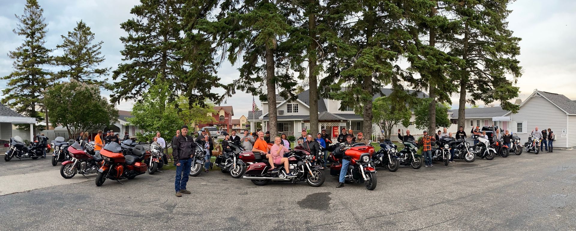 A large group of people are standing around motorcycles in a parking lot.