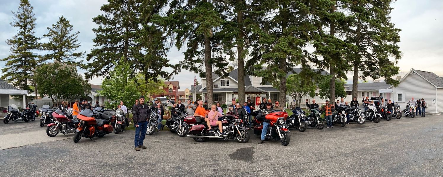 A large group of people are standing around motorcycles in a parking lot.