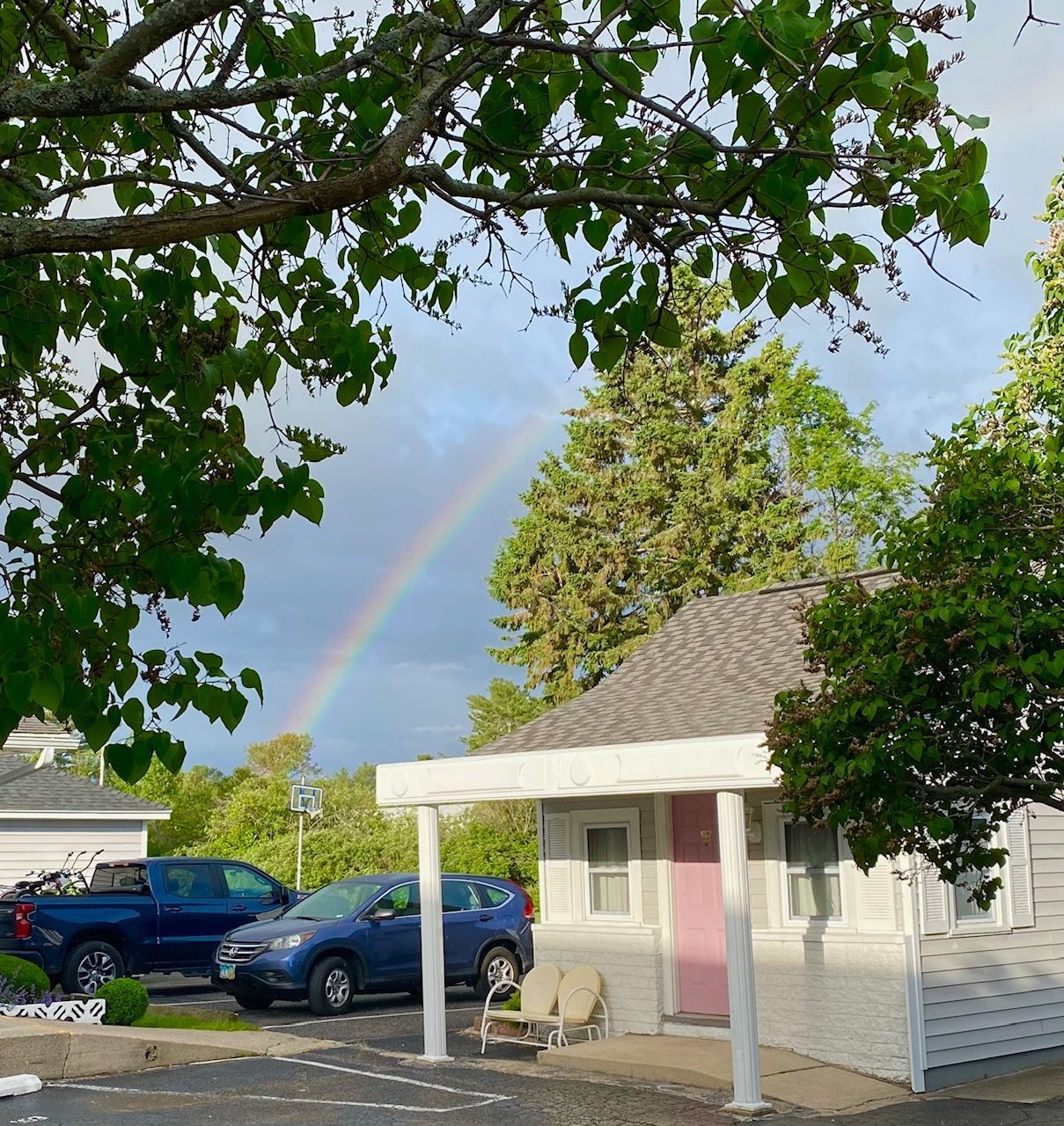 A rainbow is visible in the sky above a house