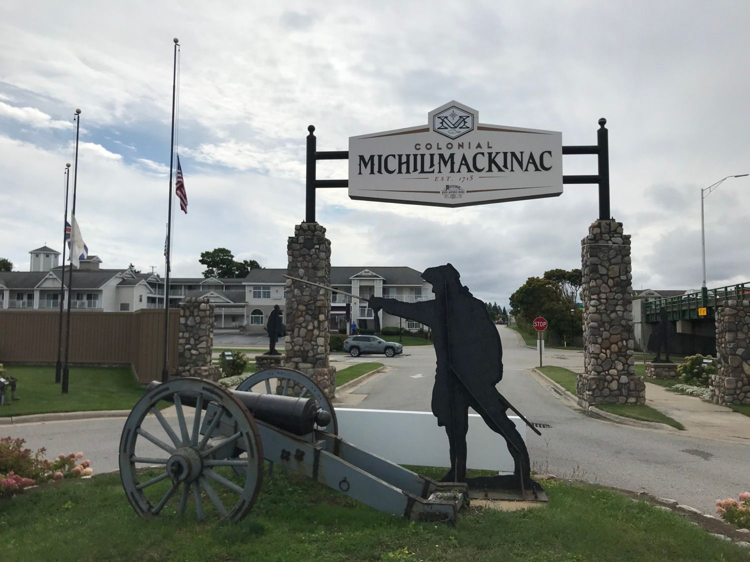 A statue of a man holding a cannon in front of a sign that says michil mackinac