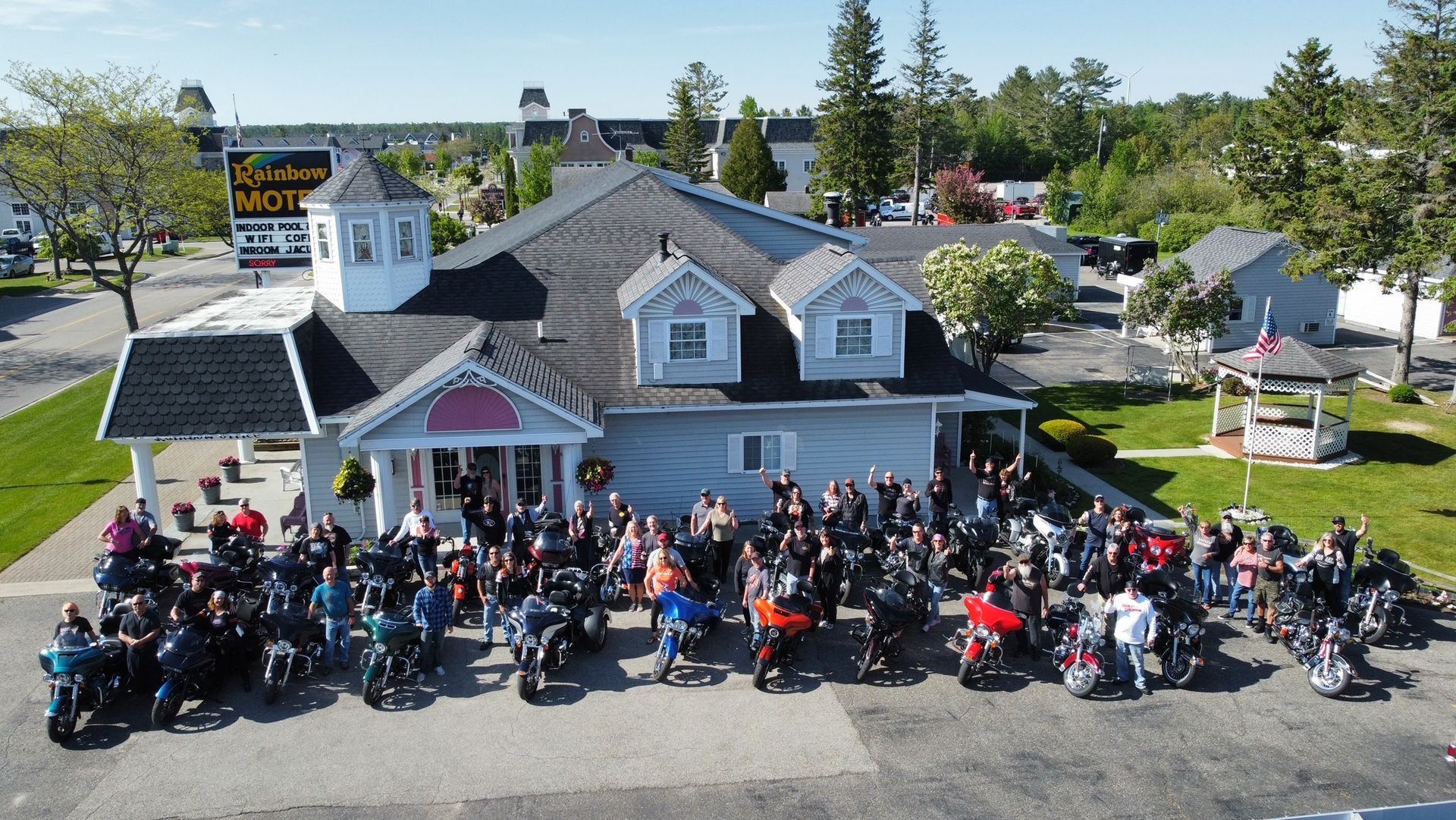 A large group of people are standing in front of a building with motorcycles parked in front of it.