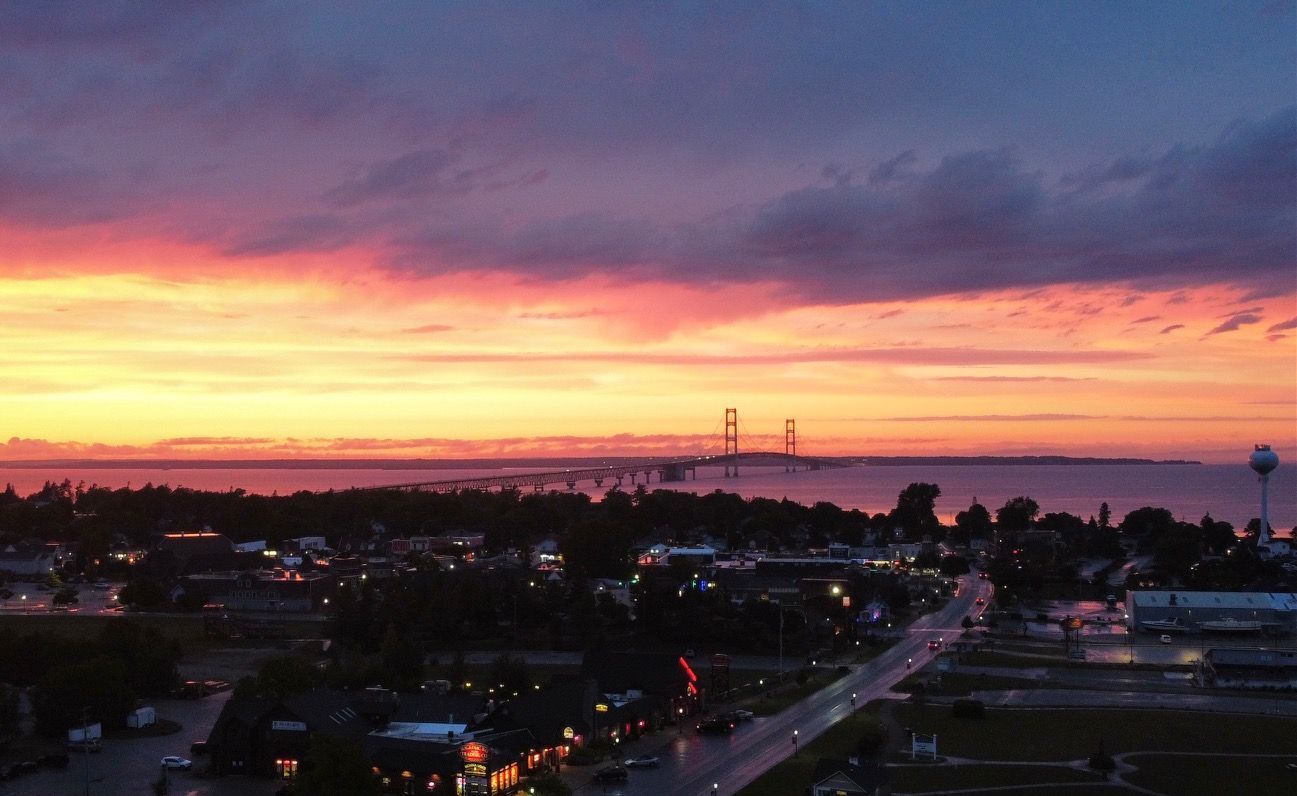An aerial view of a city at sunset with a bridge in the distance