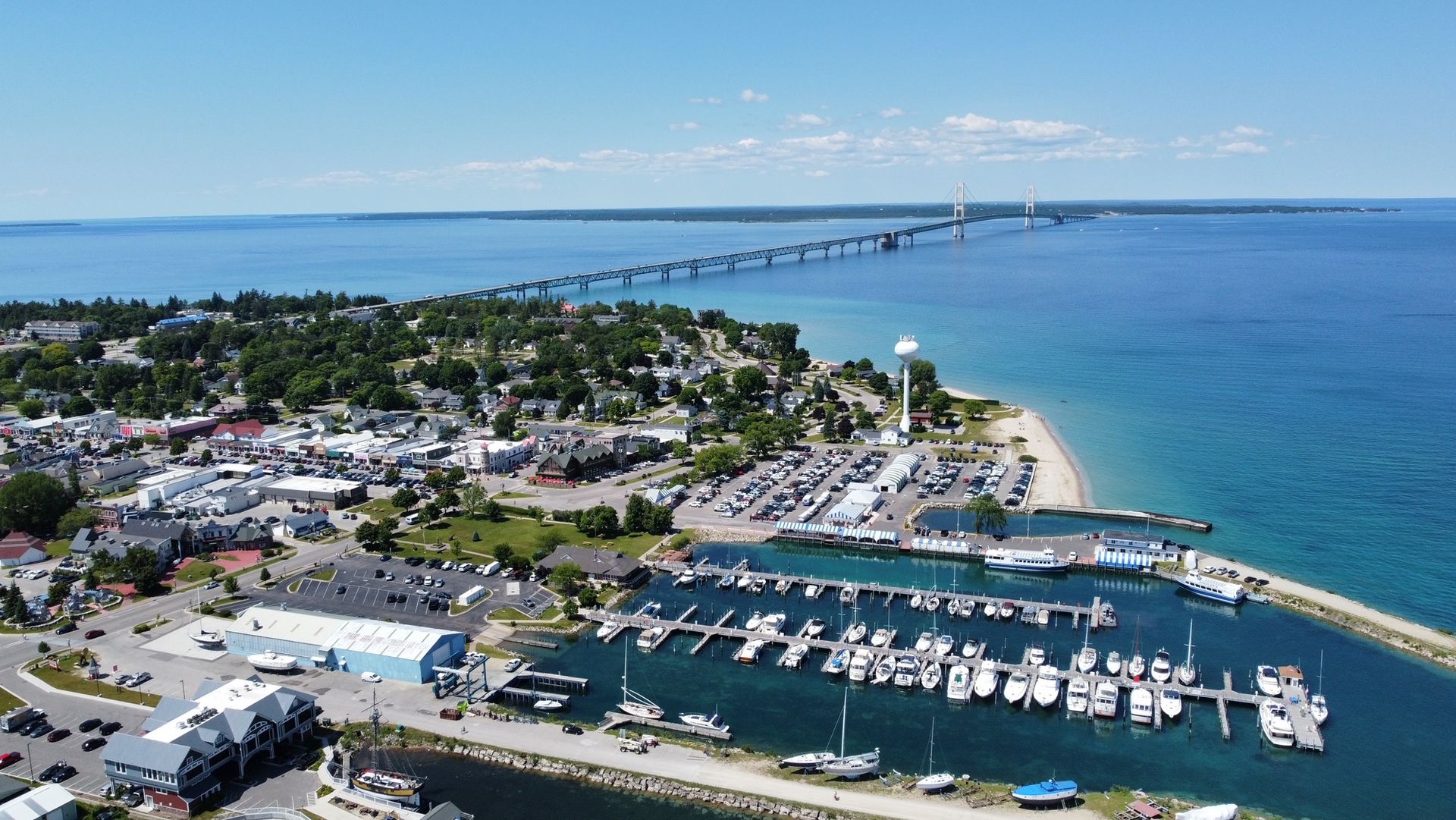 An aerial view of a marina with boats docked and a bridge in the background.