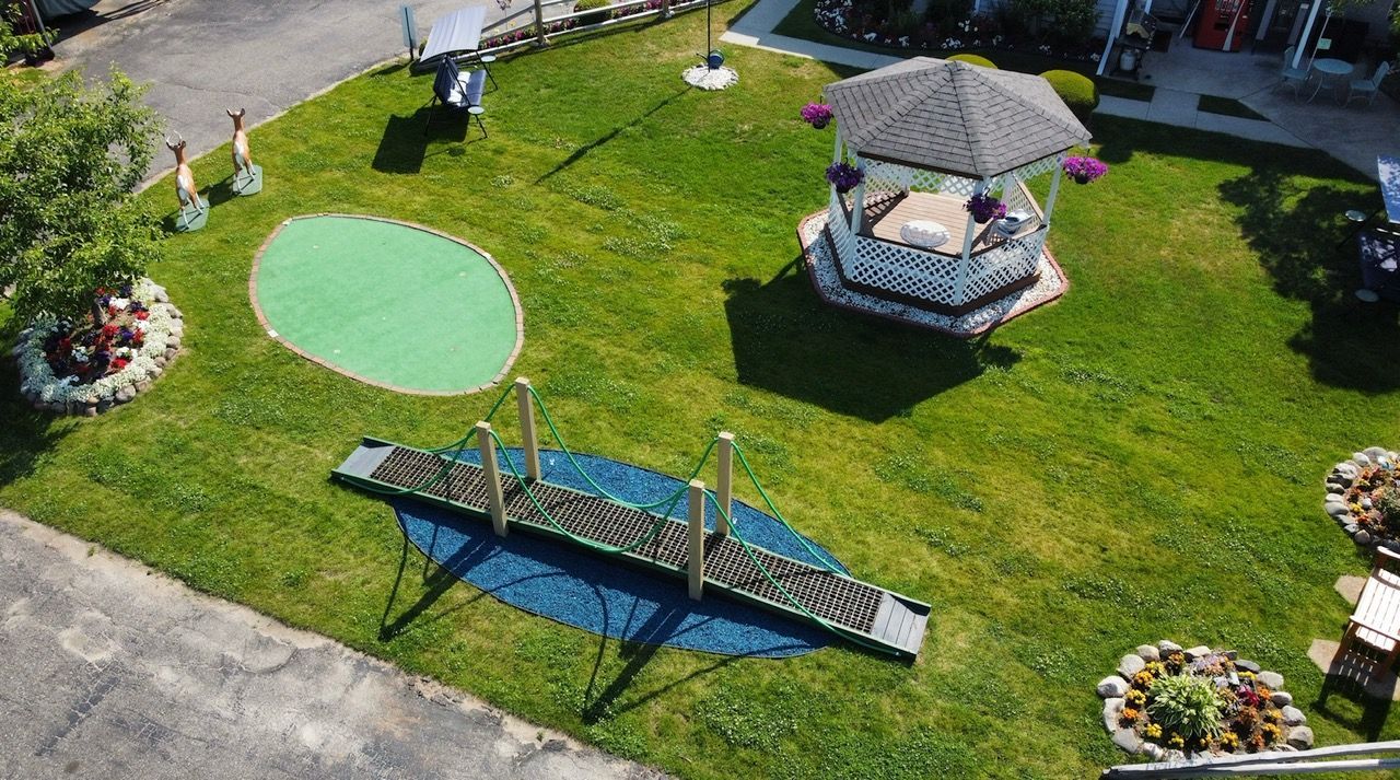 An aerial view of a lush green yard with a gazebo and a bridge.