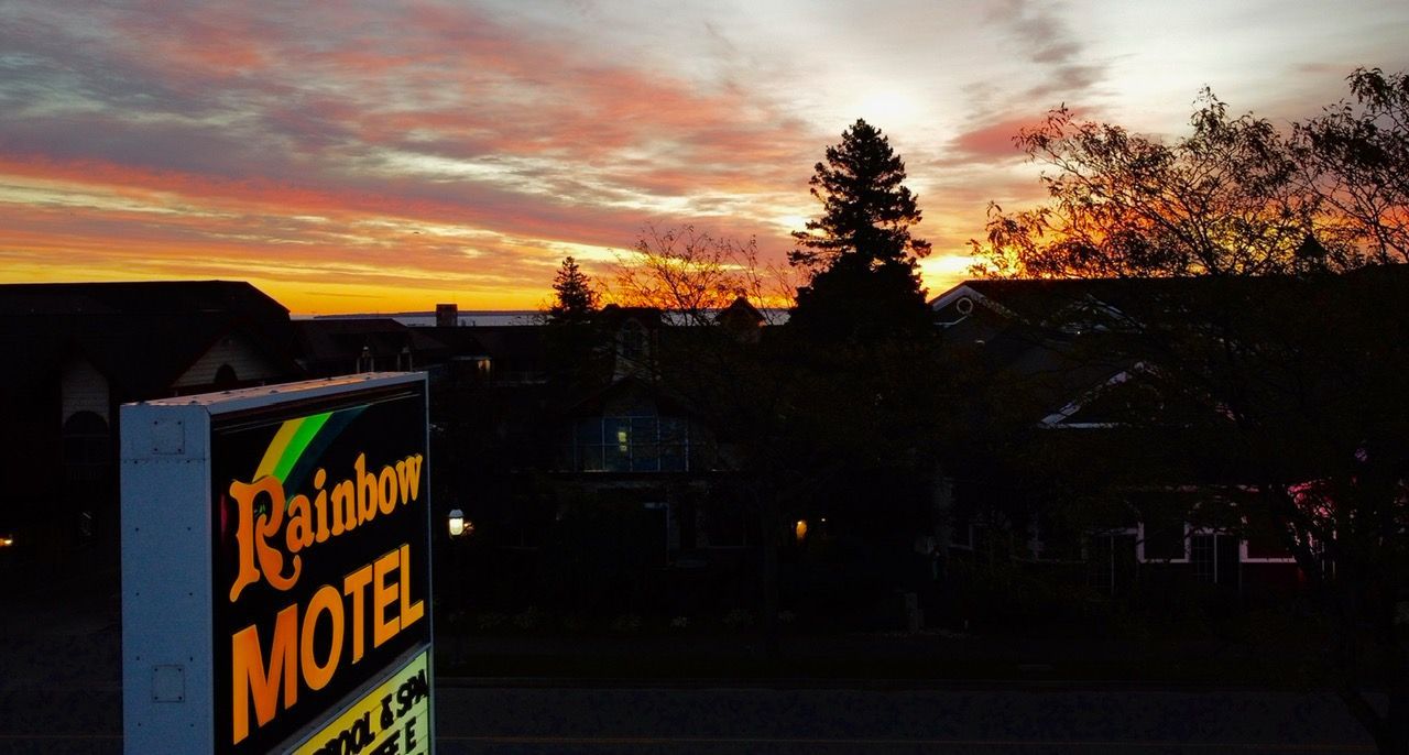 A rainbow motel sign is lit up at sunset.