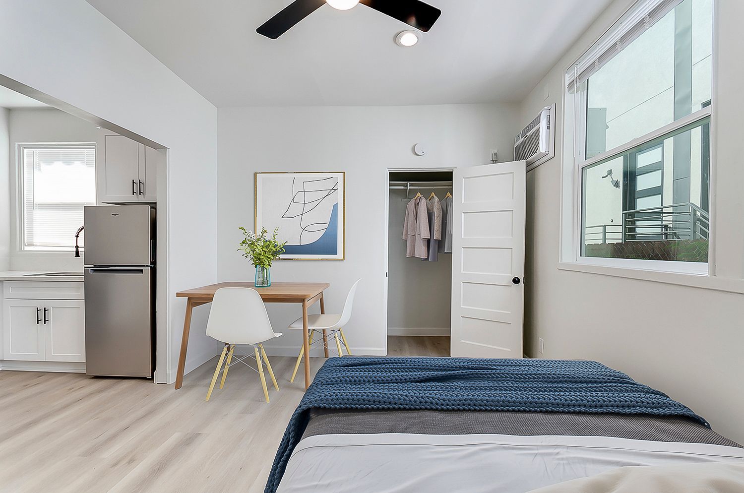 A bedroom with a bed , table , chairs and a ceiling fan.