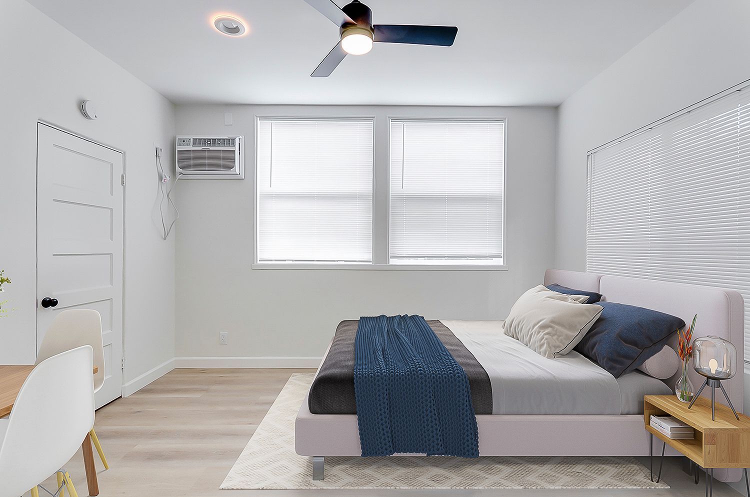 A bedroom with a bed , ceiling fan , and two windows.