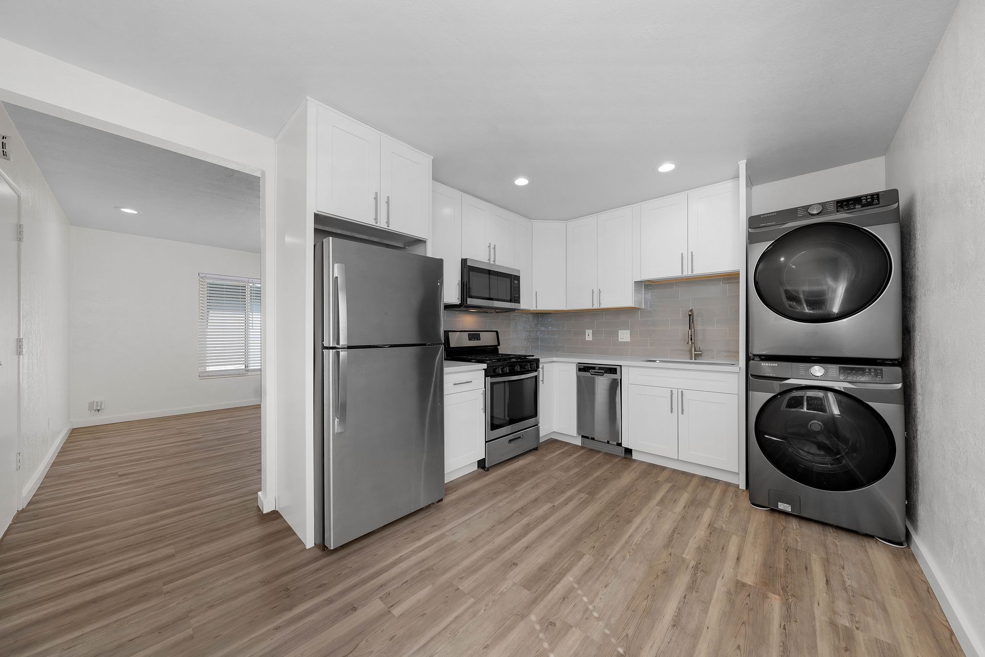 A kitchen with a refrigerator , stove , and washer and dryer stacked on top of each other.