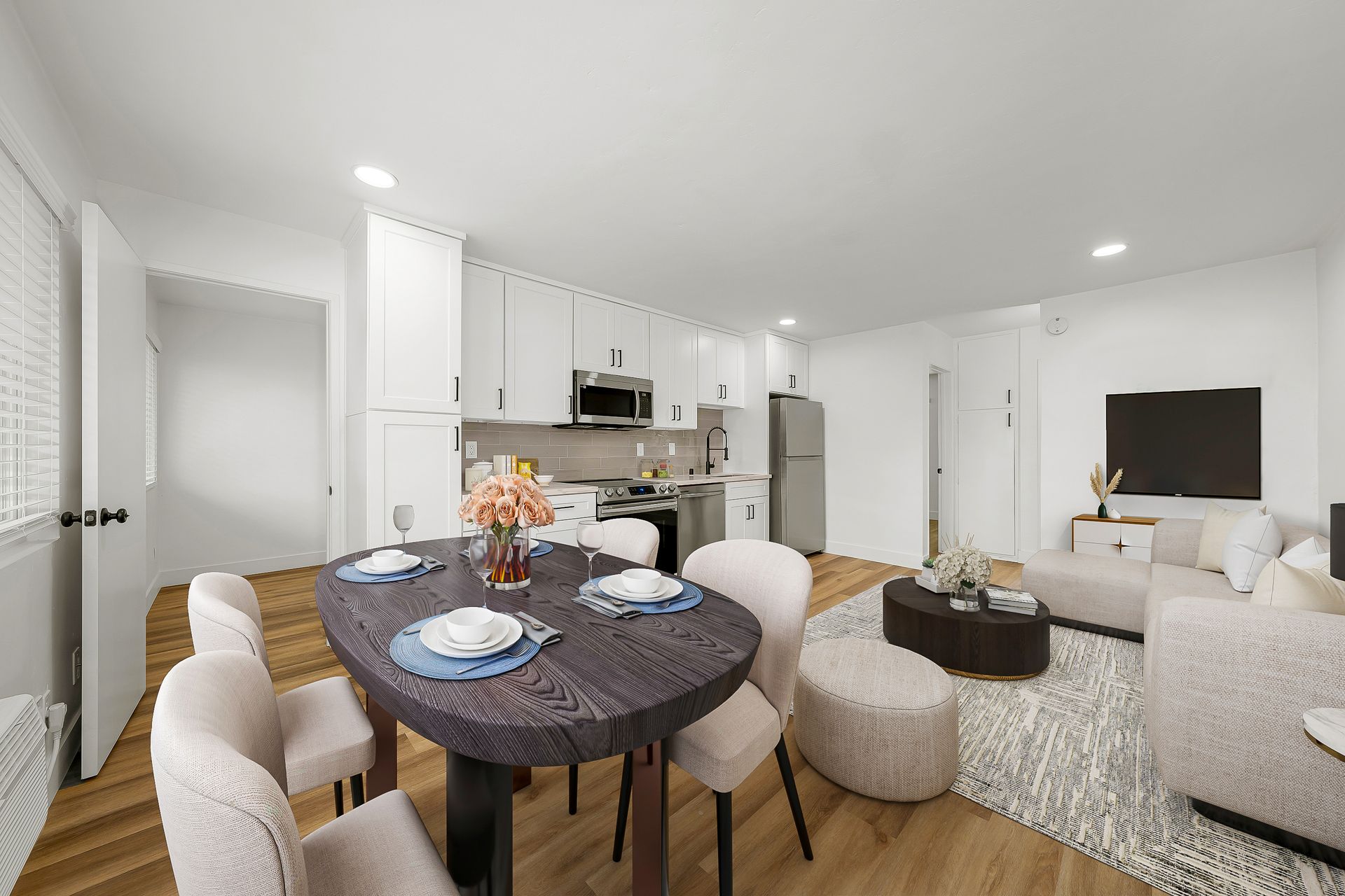 A living room with a dining table and chairs and a kitchen.
