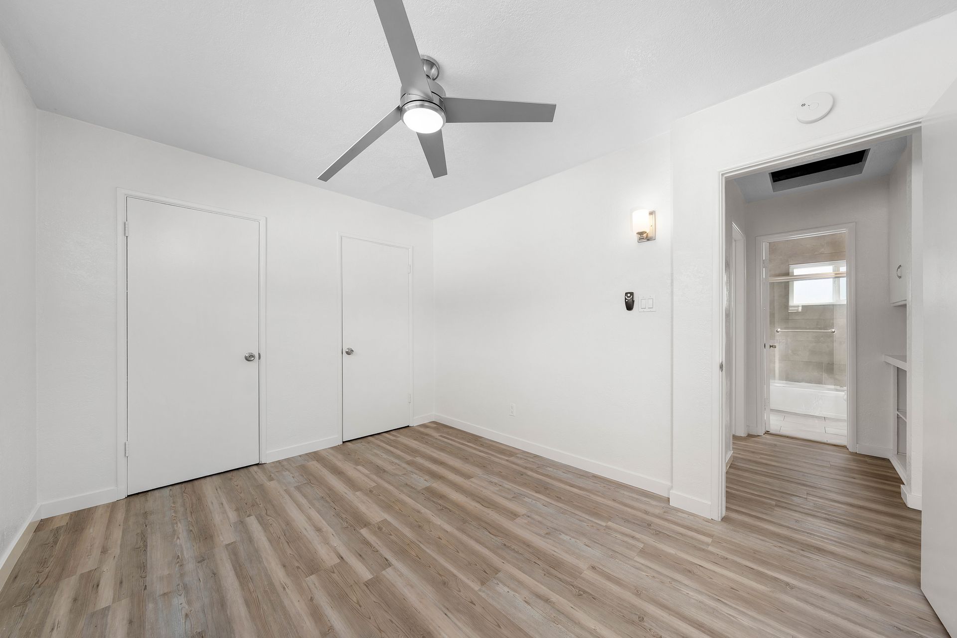 An empty room with hardwood floors and a ceiling fan.