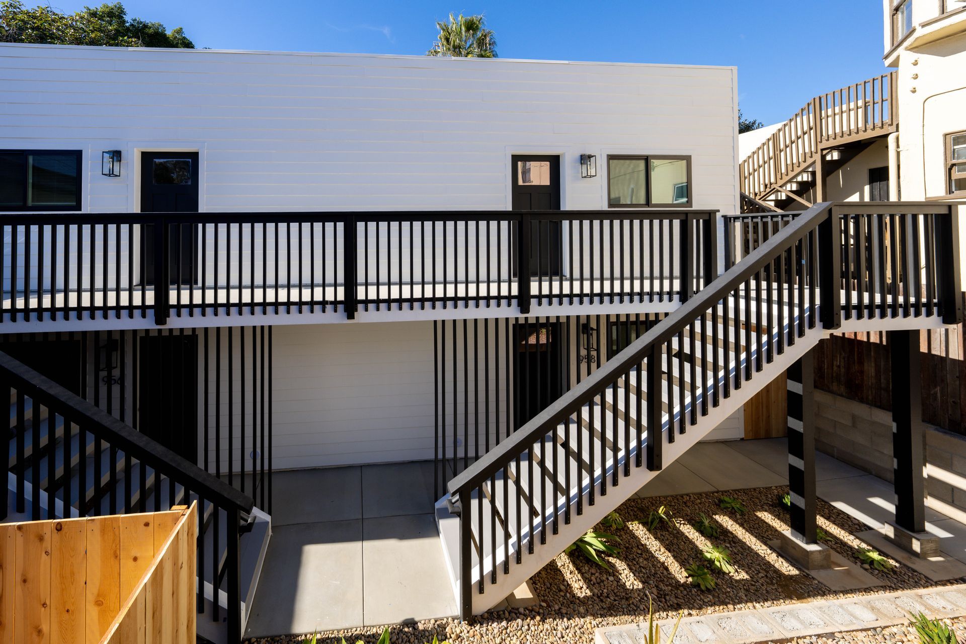 A white building with a black railing and stairs leading up to it.