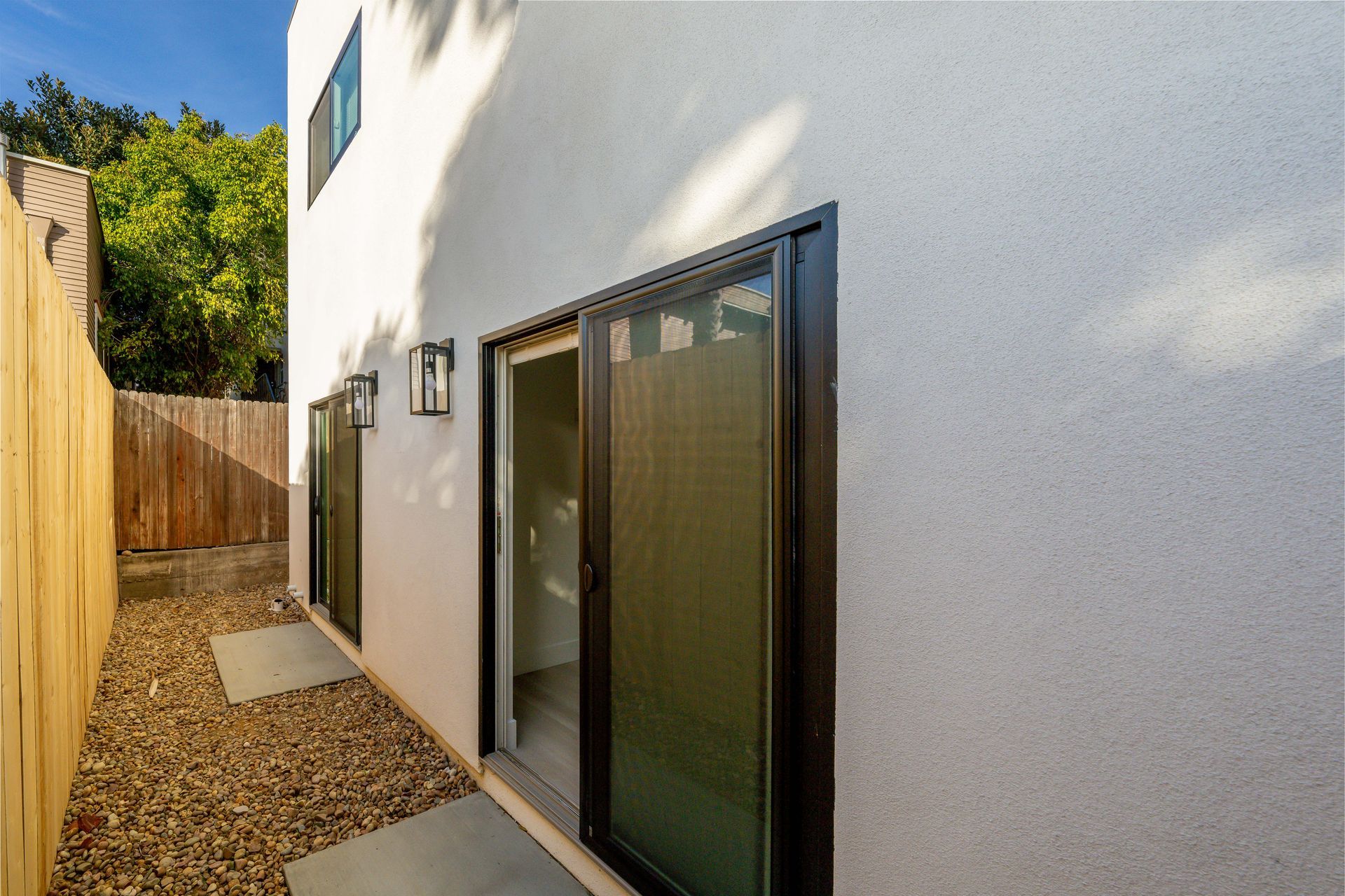 The backyard of a house with sliding glass doors and a wooden fence.